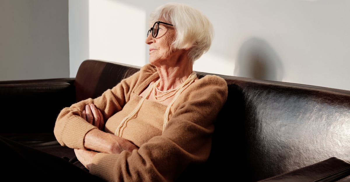 A person sits alone on an outdoor bench, looking down with a distant expression, as if unable to shake a thought that won't leave.