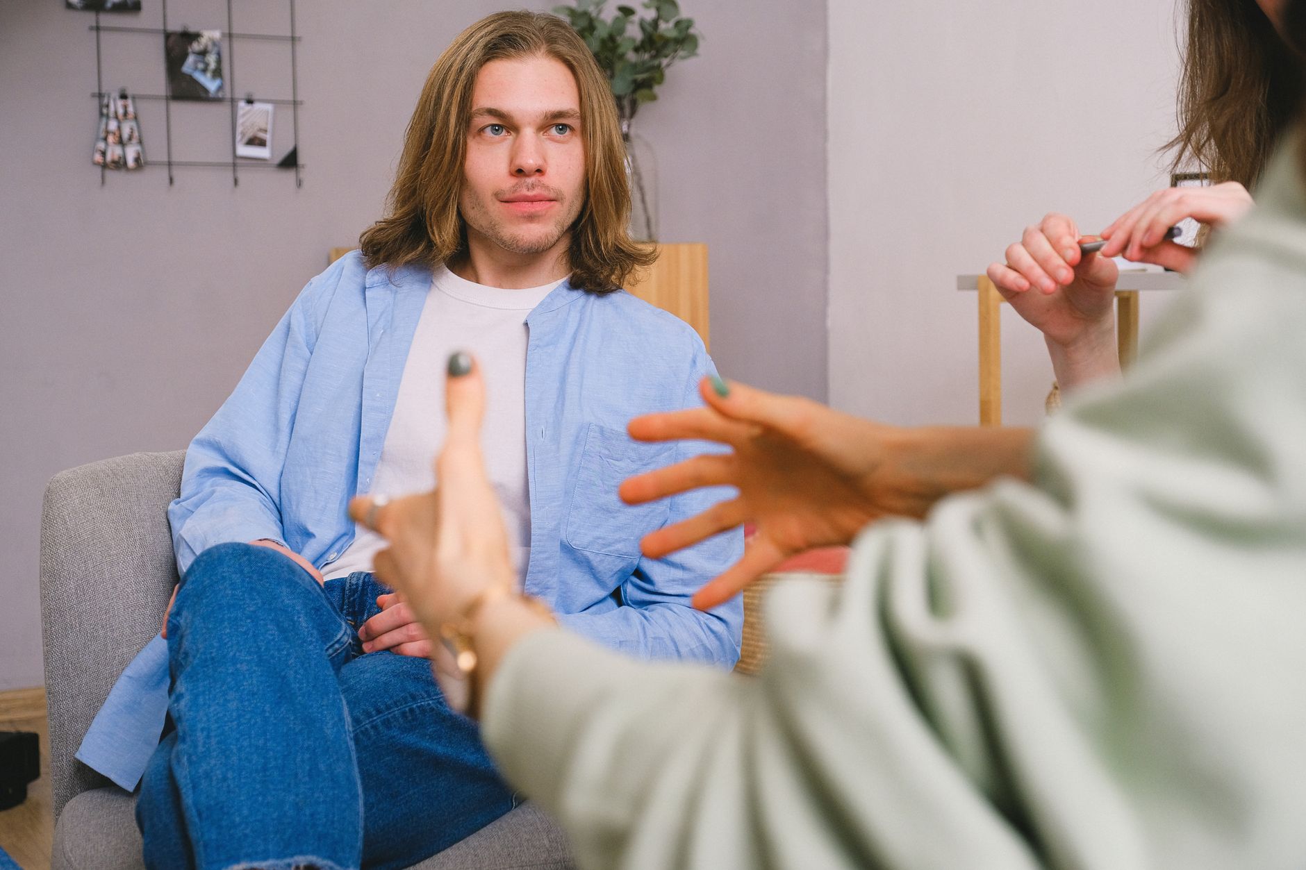 Unrecognizable therapist talking to male patient and anonymous partner during psychotherapy session in light office.